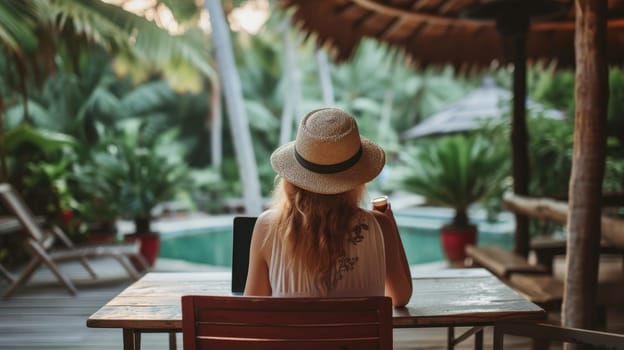 Back view of a relaxed woman with a hat, sipping coffee and overlooking a lush tropical landscape