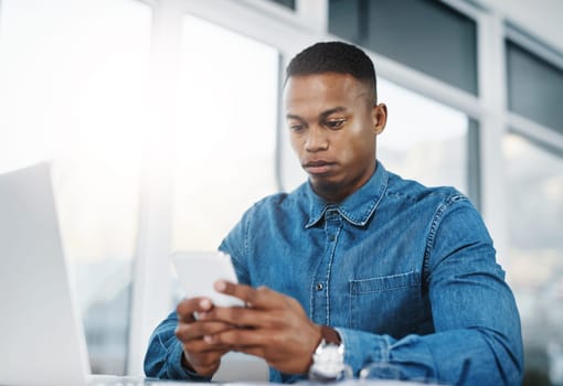 Typing, cellphone and black man by computer in office, workspace and desk happy in creative career. Communication, internship and journalist with tech for contact, research and internet for working.