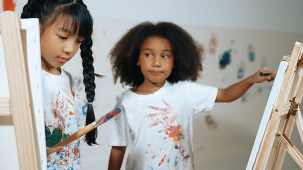 Happy creative african girl painted or draw canvas together with asian boy. Group of playful student create funny painting or artwork painted by watercolor. Creativity activity concept. Erudition.