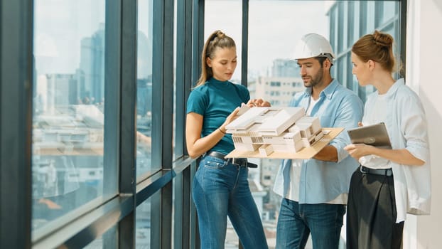 Skilled engineer holds house model and explain about house construction to skilled manager. Group of interior designer inspect architectural model. Working together, Civil engineering. Tracery