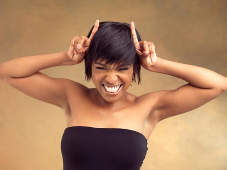 Gesture, horns or portrait of girl with hair care in studio for keratin growth, healthy shine or beauty. Devil hands, smile or face of happy black woman with style or natural glow on brown background.
