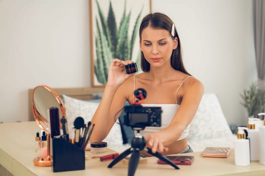 Young woman making beauty and cosmetic tutorial video content for social media. Beauty blogger smiles to camera while showing how to beauty care to audience or followers. Unveiling