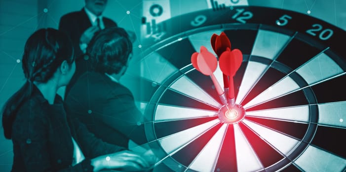 Business Target Goal For Success Strategy Concept - Red dart arrow hitting center goal on dart board with business people working in background showing precision and success of business target. uds