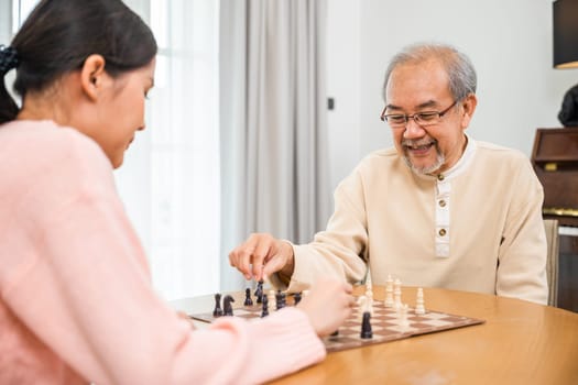 Smiling senior elderly having fun playing chess game with beautiful daughter at home, nurse caregiver in nursing home for leisure, Happy active retired people, Healthcare and medical homecare concept