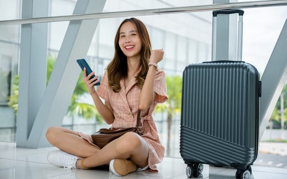 A female traveler sitting on the ground with a suitcase and smartphone, contemplating her journey. She enjoys the peaceful solitude of travel. Adventure is her escape.