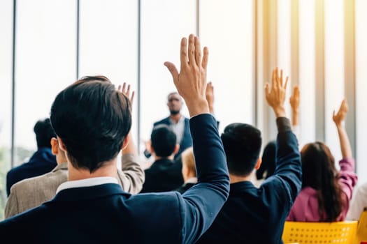 In the boardroom business professionals meet for a strategy session. The meeting and seminar feature raised hands as questions are posed by colleagues and employees.