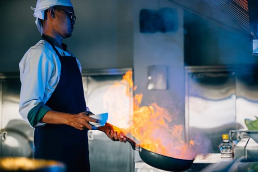 Closeup of chef hands in professional kitchen handling flaming wok. Expertise at work flames cooking food. Skilled chef busy in modern kitchen with flames. cook food with fire