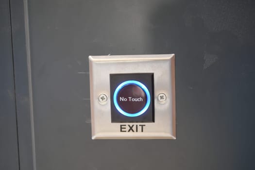 Close up of an exit button on a hardwood door in electric blue font.
