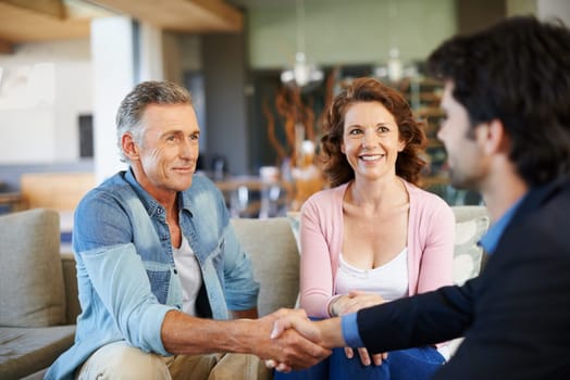 Mature couple, broker and handshake in house for mortgage for retirement in planning, finances and advice. Man, woman and consultant for pension, deal or agreement in lounge with advisor in thank you.
