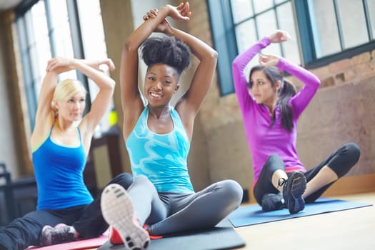 Black woman, portrait and trainer at yoga class, stretch and yogi instructor for exercise. People, friends and confident for pilates or spiritual fitness, flexibility and happy for group activity.