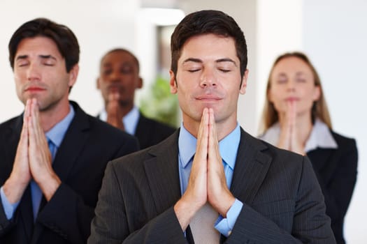 Business people, pray and meditation with hands together in team for faith, calm or company peace at office. Young businessman, colleagues or coworkers meditating in belief, spiritual wellness or zen.