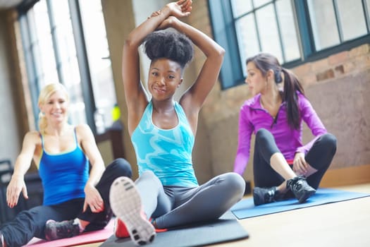 Black woman, portrait and yoga class at gym, stretch and yogi instructor for exercise on mat. People, friends and confident for pilates or spiritual fitness, flexibility and happy for group activity.