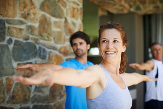 Woman, pose and happy in yoga class for fitness and mental wellbeing, workout and daily lesson to coach people. Female yogini, warrior posture and yogis or students practice strength and balance