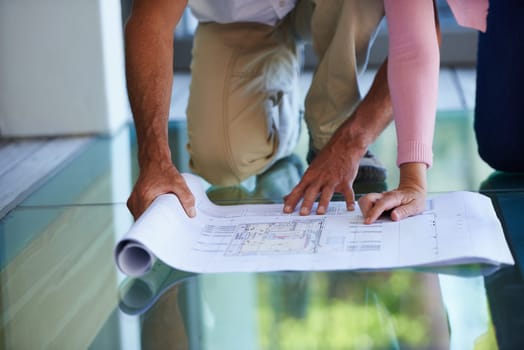 People, hands and planning with blueprint for interior design, maintenance or renovation at house. Closeup of contractor or building team with paperwork, document or floor layout for home improvement.