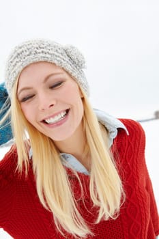 Face, snow and happy woman in winter with smile, beanie or jersey in Sweden on holiday vacation. Female person, joy or funny girl walking on outdoor trip for travel, adventure or wellness in nature.