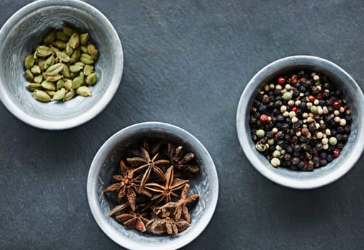 Food, ingredients and spices in bowl on board for cooking Indian cuisine, meal and lunch. Flavour, culinary and seasoning for gourmet dinner with cardamon seeds, star anise and peppercorn.