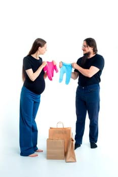 young pregnant woman and her husband with shopping bags andchoose blue for a boy or pink for a girl on white background. Pregnancy shopping concept happy young family with shopping bags