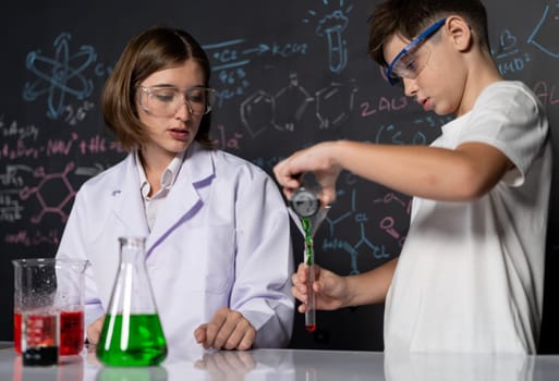 Teacher support schoolboy in laboratory. Schoolboy and teacher stand and experiment about science of chemistry in STEM class using liquid in glass container. Instructor mixing solution. Erudition.