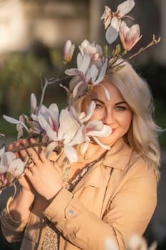 Magnolia flowers woman. A woman is holding a magnolia flower in her hand and standing in front of a tree. Concept of serenity and beauty, as the woman is surrounded by nature and the flower adds a touch of color