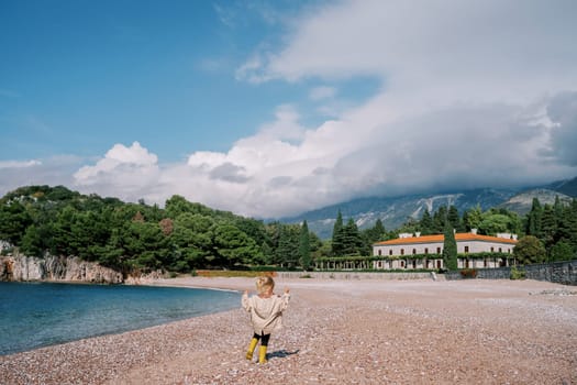 Little girl walks along the royal beach near Villa Milocer. Montenegro. Back view. High quality photo