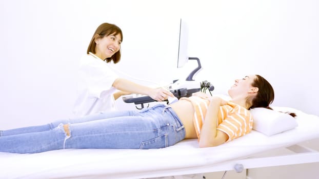 Female doctor informs a patient that she is pregnant during an ultrasound lying on stretcher on a clinic