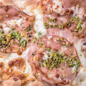Gourmet pizza with mortadella, pistachio grains and mozzarella.