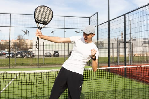 European man holding padel racquet in hand and ready to return ball while playing in court. High quality photo