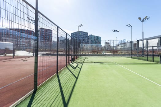 Landscaped areas of a residential development with a tennis court with high Plexiglas and metal fences. High quality photo