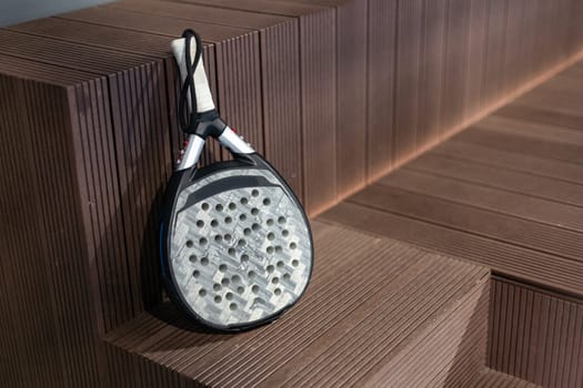 Closeup view of a paddle racket in a padel tennis court near the net. Sport, health, youth and leisure concept. Sporty equipment. White lines in background. High quality photo