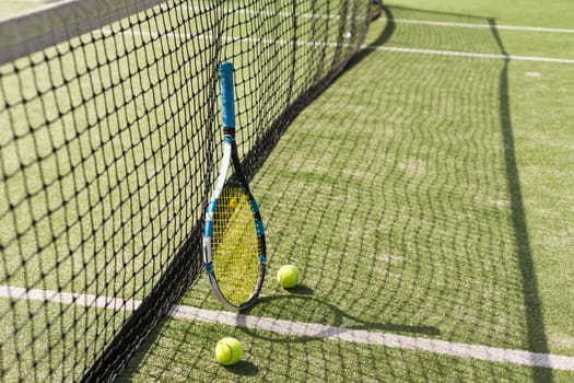 Tennis racquet and tennis balls at the net on the lines on a tennis court. . High quality photo