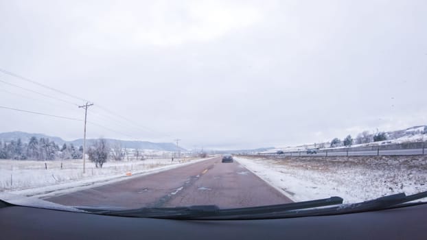 The open highway invites a peaceful drive, with snow-clad pines lining I-25 as the journey continues from Denver towards Colorado Springs on a snowy day.