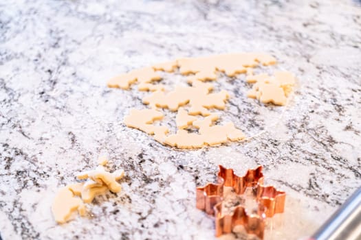 Enjoy the festive tradition of rolling out cookie dough and cutting snowflake-shaped sugar cookies, perfect for the holiday season.