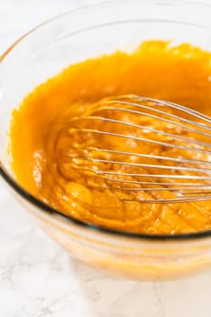 A close-up view of expertly blended ingredients in a large mixing bowl for a mouthwatering homemade pumpkin bundt cake.