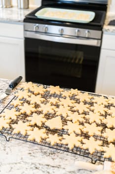 Letting delightful snowflake-shaped sugar cookies cool on a rack, preparing them for festive Christmas gifts.