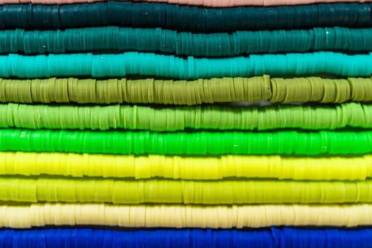 A vibrant collection of clay beads, neatly arranged by color on a white table, ready to inspire young crafters to create their own unique bracelets.