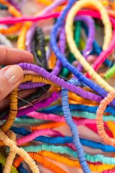 A vibrant collection of clay beads, neatly arranged by color on a white table, ready to inspire young crafters to create their own unique bracelets.