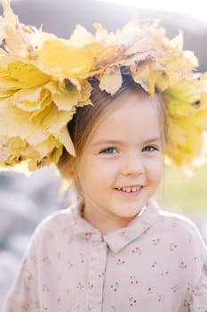 Little happy girl in a wreath of autumn leaves. Portrait. High quality photo