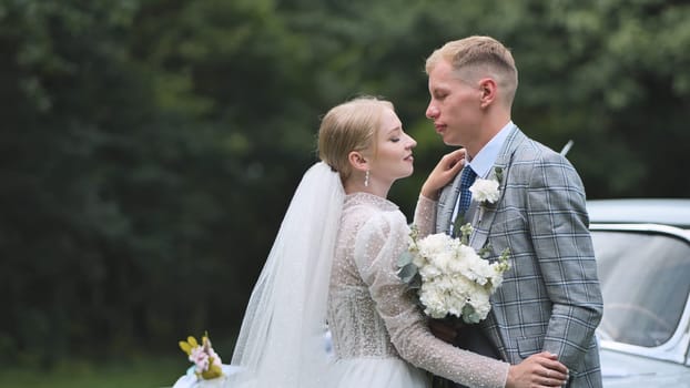 Newlyweds on their wedding day against the backdrop of a retro car