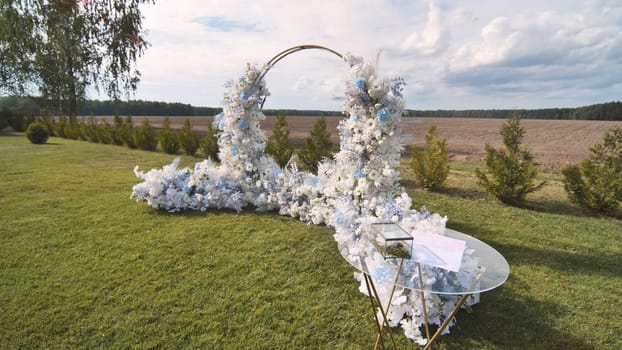 The wedding arch decorated with flowers stands in the luxurious area of the wedding ceremony.