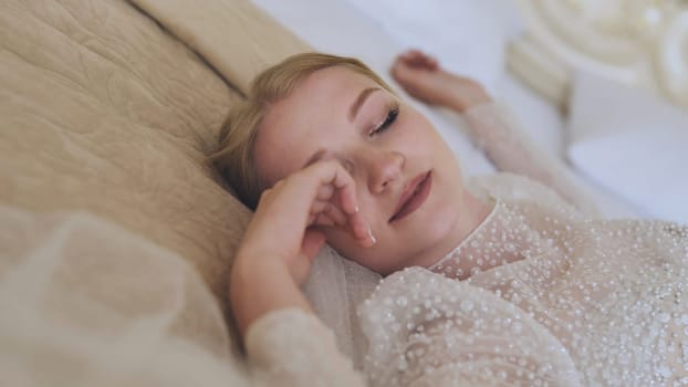 The delicate bride lies and poses on the bed