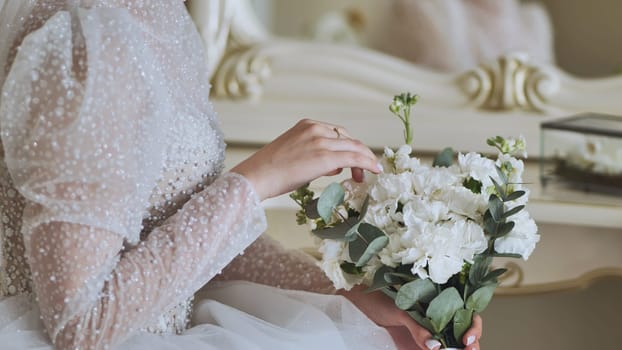 The bride touches the bouquet of flowers