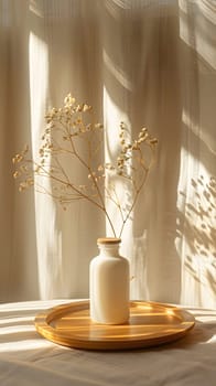 A glass vase with dried flowers rests on a wooden tray atop a table, adding a touch of nature and color to the rooms interior design