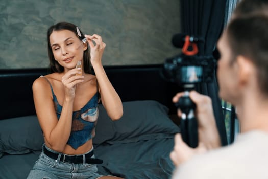 Man filming video on young woman making beauty and cosmetic tutorial video content for social media. Beauty blogger smiles to camera while showing how to beauty care to audience or follower. Unveiling