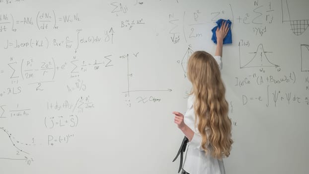Caucasian woman erasing formulas from white board