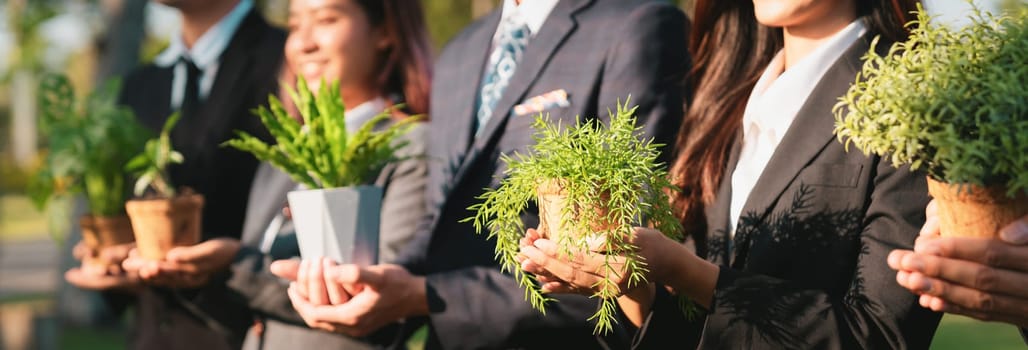 Business people holding plant as concept of eco company committed to corporate social responsible, reducing CO2 emission, protect environment, and embrace ESG principle for sustainable future. Gyre