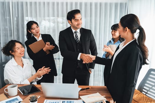 Group of businesspeople shake hand after made successful business agreement meeting. Diverse race office worker celebrate after made progress on marketing planning in corporate office. Meticulous