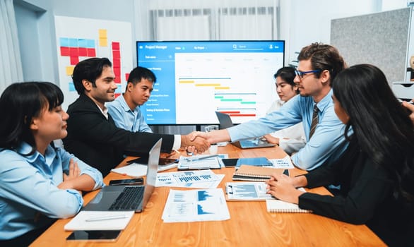 Cheerful meeting room, businesspeople celebrate with handshaking. Successful project was completed before the deadline. Business partnership and collaboration in project management. Habiliment