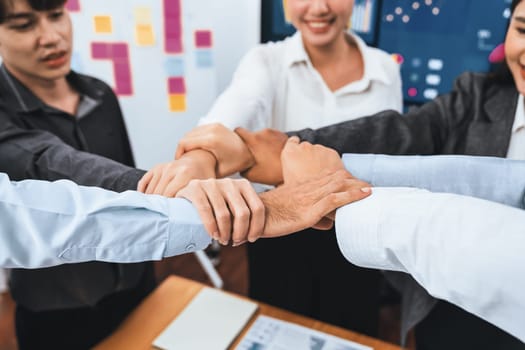 Diverse team of officer workers hold hands in circle, showing solidarity and teamwork in corporate office. Businesspeople form strong community built on integrity and collaboration. Concord