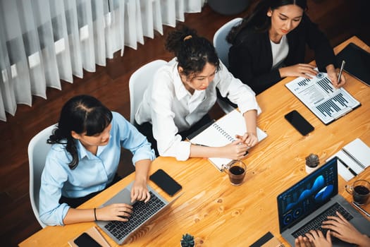 Wide top view of diverse group of business analyst team analyzing financial data report paper on meeting table. Chart and graph dashboard by business intelligence analysis. Meticulous