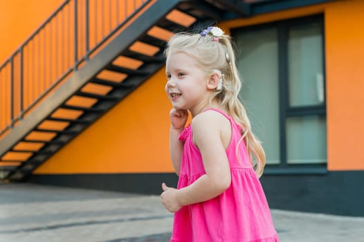 Child with hearing problem and cochlear implant dance in street, deaf kid began to hear. Hearing loss in childhood and treatment concept. Copy space and empty place for text.